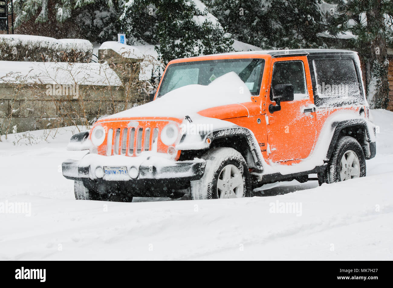 Hamilton, Ontario, Canada - February 2013: A snow covered jeep parked at the roadside during severe snowfall Stock Photo