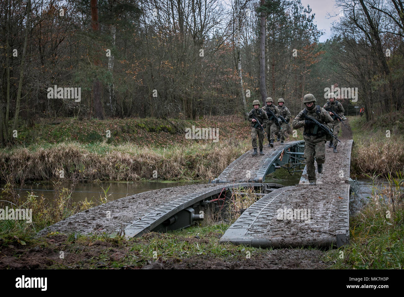 Polish Soldiers assigned to 10th Armored Cavalry Brigade run across a temporary bridge during a crossing exercise near the Kwisa River in Poland on Nov. 16, 2017. The U.S. Army, its allies and partners forge a dynamic presence with a powerful land network that simultaneously deters aggression and assures the security of the region.  (Photo by U.S. Army Spc. Dustin Biven / 22nd Mobile Public Affairs Detachment) Stock Photo