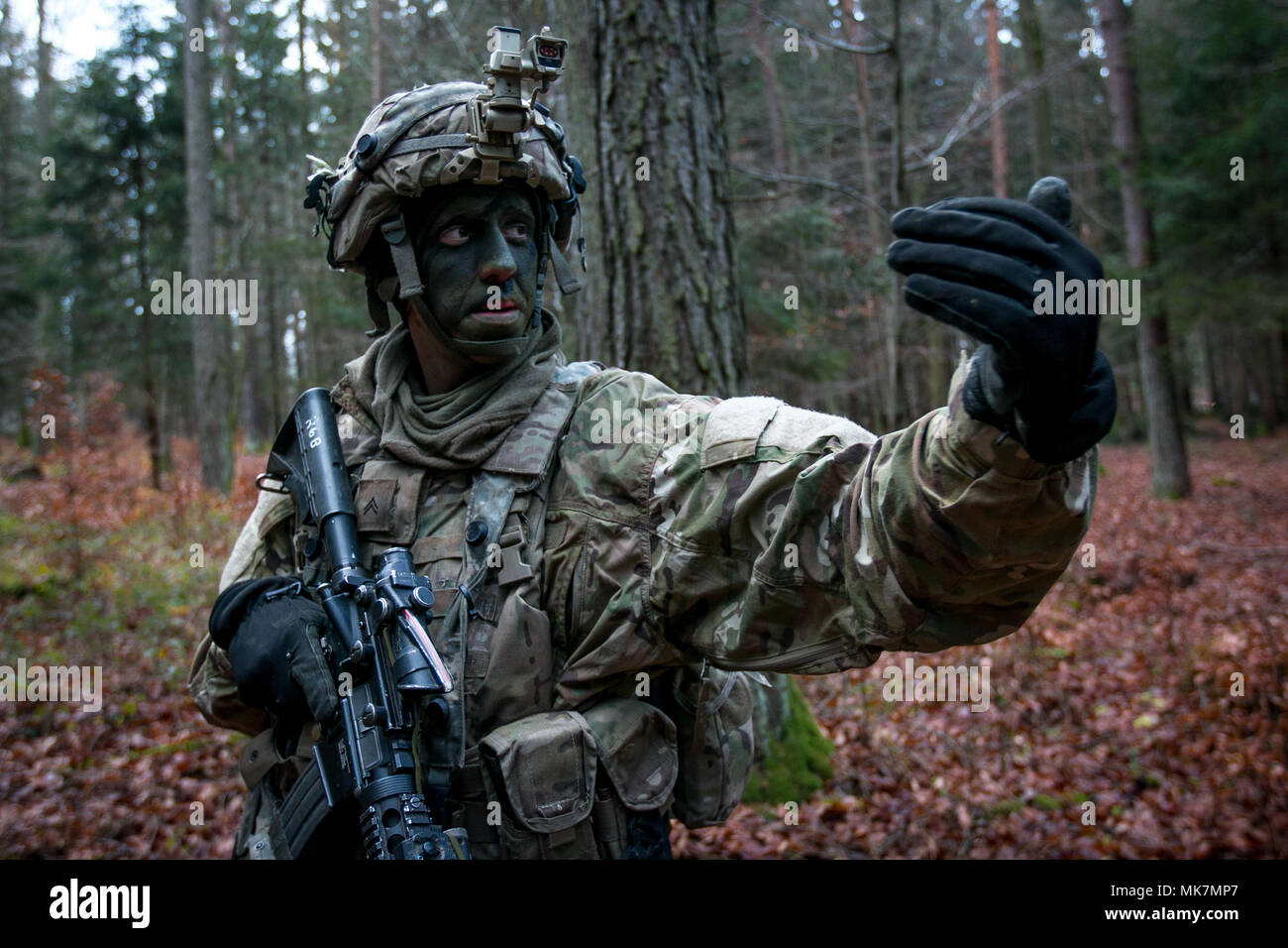 Cpl. Brad Olin, assigned to Company C, 2nd Battalion, 70th Armor Regiment, 2nd Armored Brigade Combat Team, 1st Infantry Division from Fort Riley, Kansas signals to his team to continue to advancing towards their objective on Nov. 18, 2017 during an Allied Spirit VII training event in Grafenwoehr, Germany. The U.S. Army, along with its allies and partners, continues to forge a dynamic presence with a powerful land network that simultaneously deters aggression and assures the security of the region. Approximately 3,700 service members from 13 nations gather together in 7th Army Training Command Stock Photo