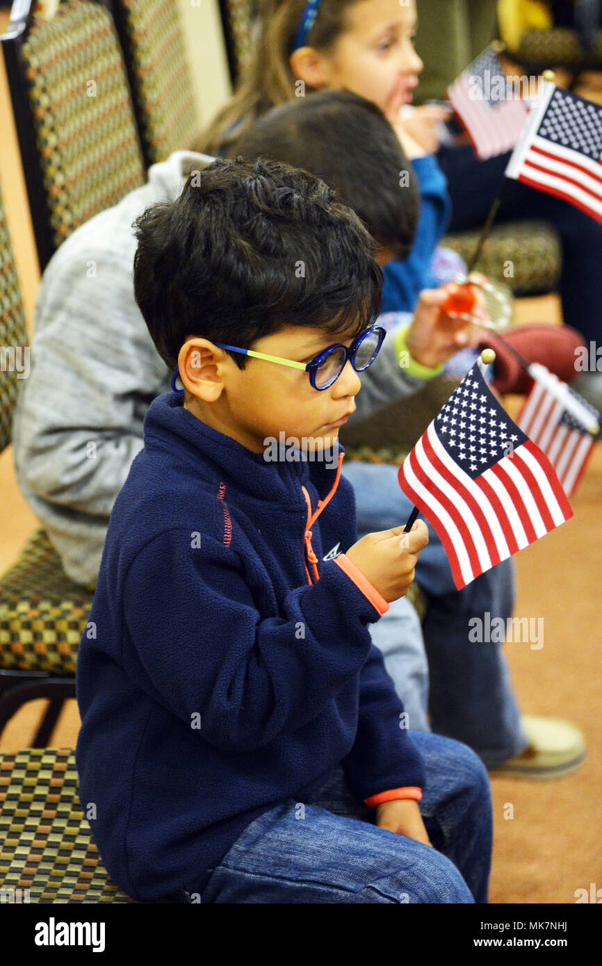 A young boy watches his mother take her oath of citizenship and