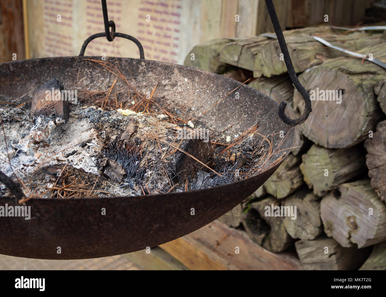 Ashes Burning in The Hanging Stove with The Firewood on Brick Wall and Wooden Background Stock Photo