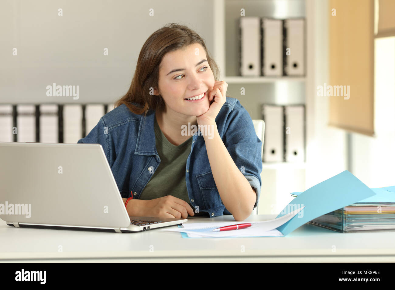 Smiley intern dreaming looking at side at office Stock Photo