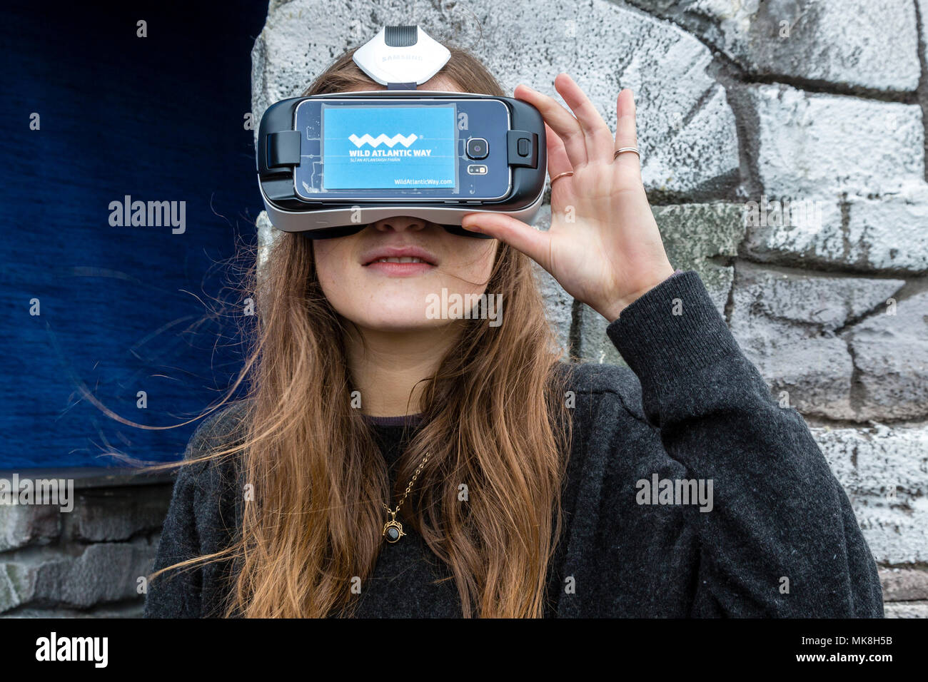 Young women wearing VR headset to view travel destination on the Ring of Kerry,  used by the Irish tourist board to promote the Skellig Rocks Stock Photo