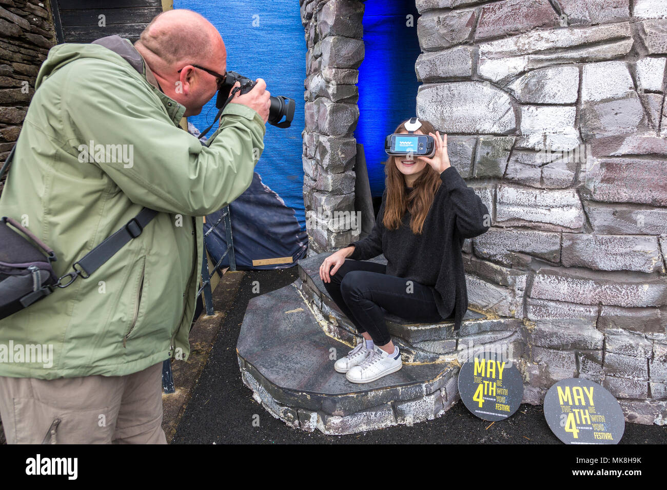 Young woman being photographed wearing VR headset to view travel destination on the Ring of Kerry, Stock Photo