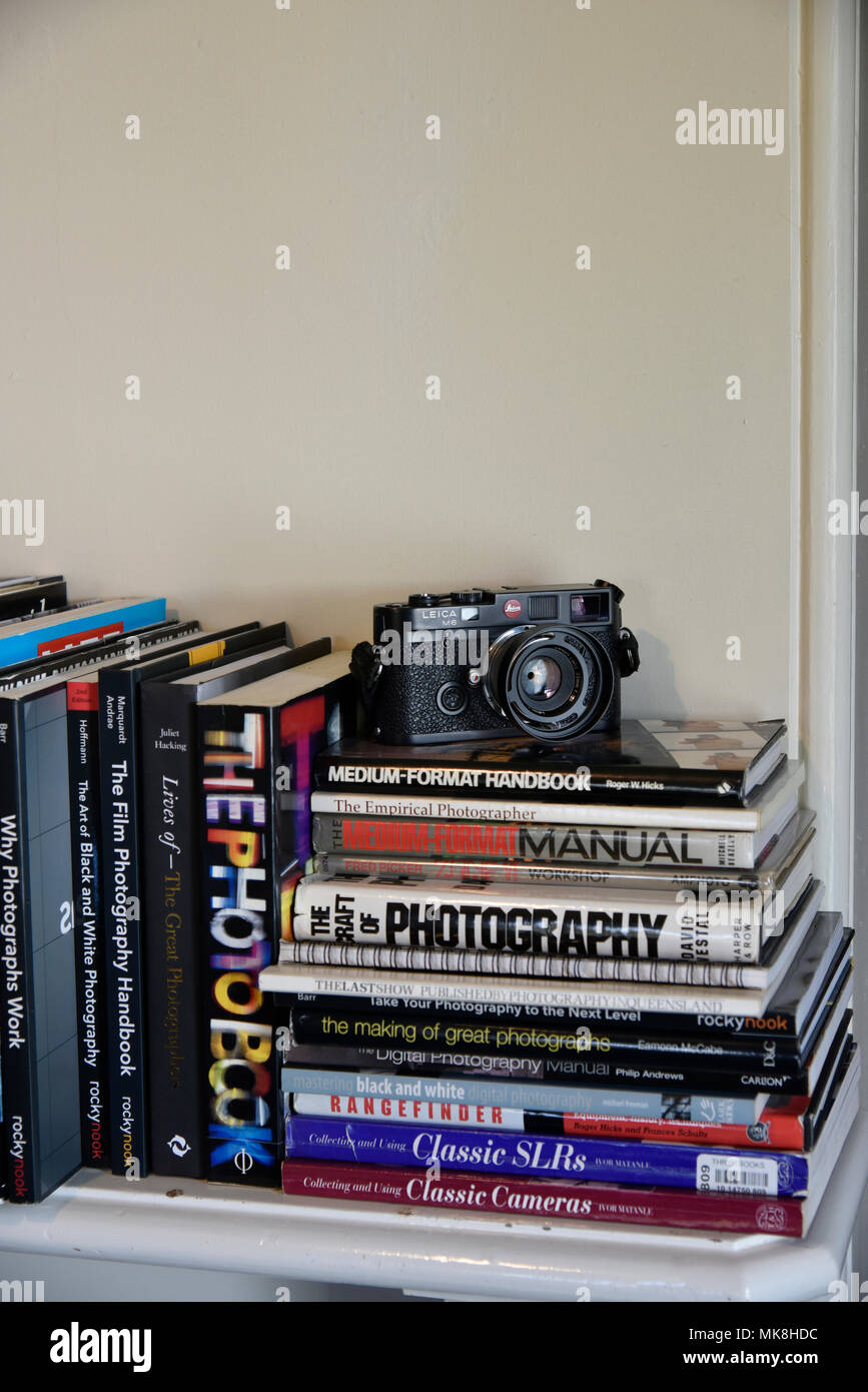 leica m6 rangefinder camera on pile of photography books on mantlepiece Stock Photo