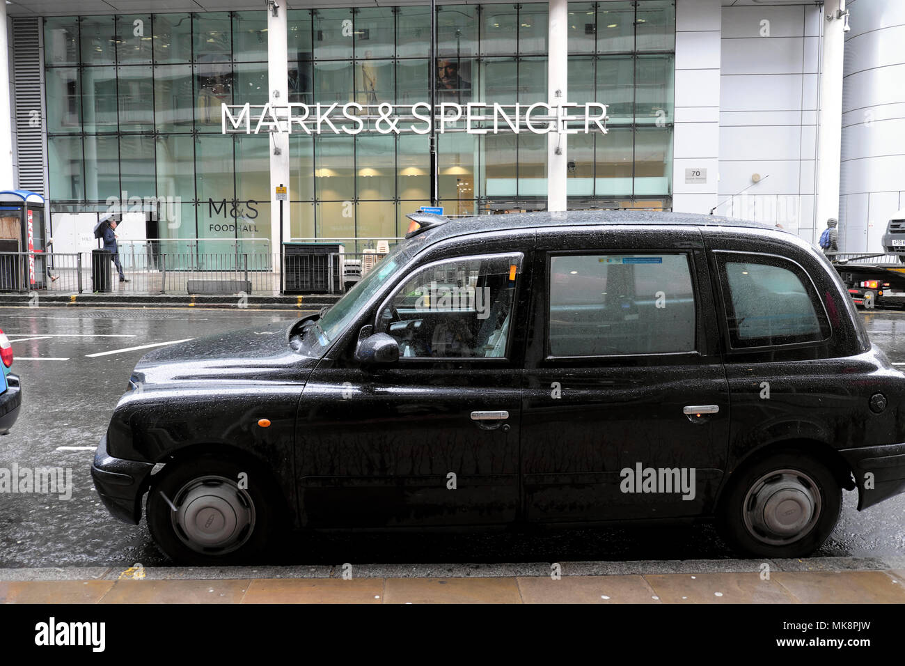 Taxi parked outside Marks & Spencer store in Moorgate on a rainy day in spring in the City of London UK  KATHY DEWITT Stock Photo