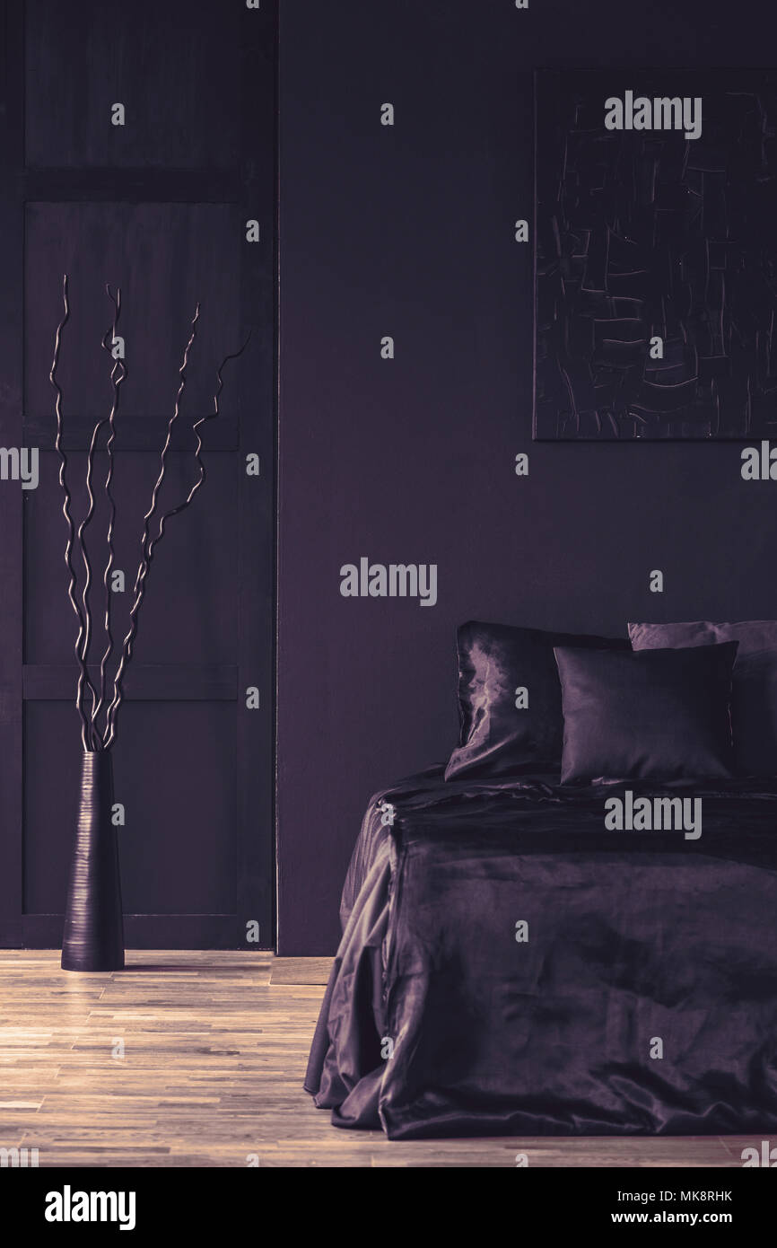 Metal sculpture next to bed with black bedding in monotone bedroom ...
