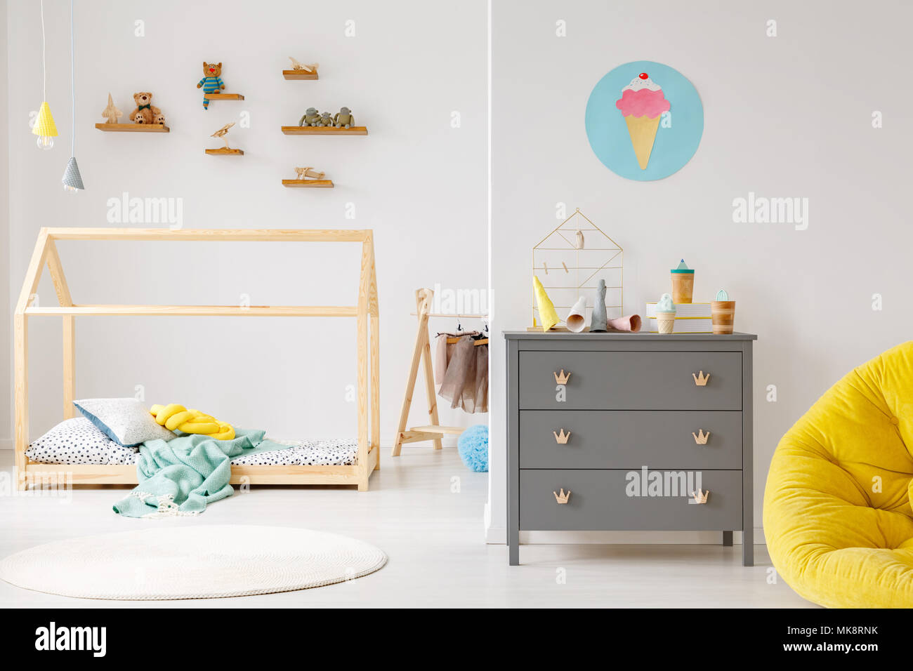 Grey cabinet against white wall with poster in modern child's room interior with wooden bed Stock Photo