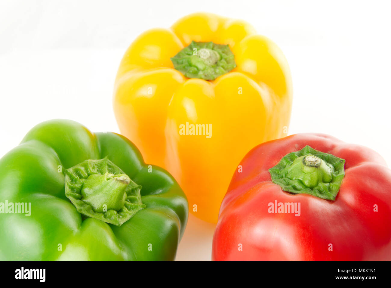Green, red and yellow peppers isolated on a white background composed
