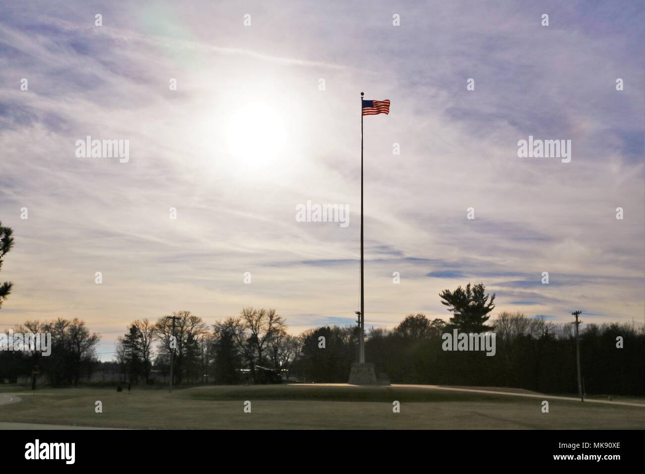 The flag of the United States of America is brightened by a backdrop of afternoon sun Nov. 27, 2017, while flying on the flagpole in front of Garrison Headquarters at Fort McCoy, Wis. The weather for late November was unseasonably warm with temperatures around 50 degrees Fahrenheit. (U.S. Army Photo by Scott T. Sturkol, Public Affairs Office, Fort McCoy, Wis.) Stock Photo