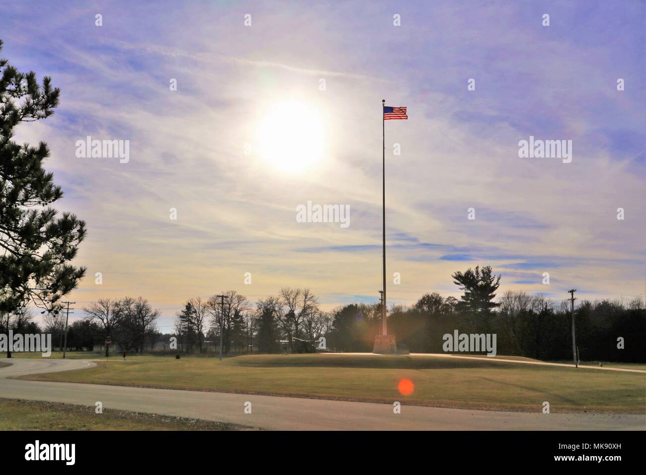 The flag of the United States of America is brightened by a backdrop of afternoon sun Nov. 27, 2017, while flying on the flagpole in front of Garrison Headquarters at Fort McCoy, Wis. The weather for late November was unseasonably warm with temperatures around 50 degrees Fahrenheit. (U.S. Army Photo by Scott T. Sturkol, Public Affairs Office, Fort McCoy, Wis.) Stock Photo