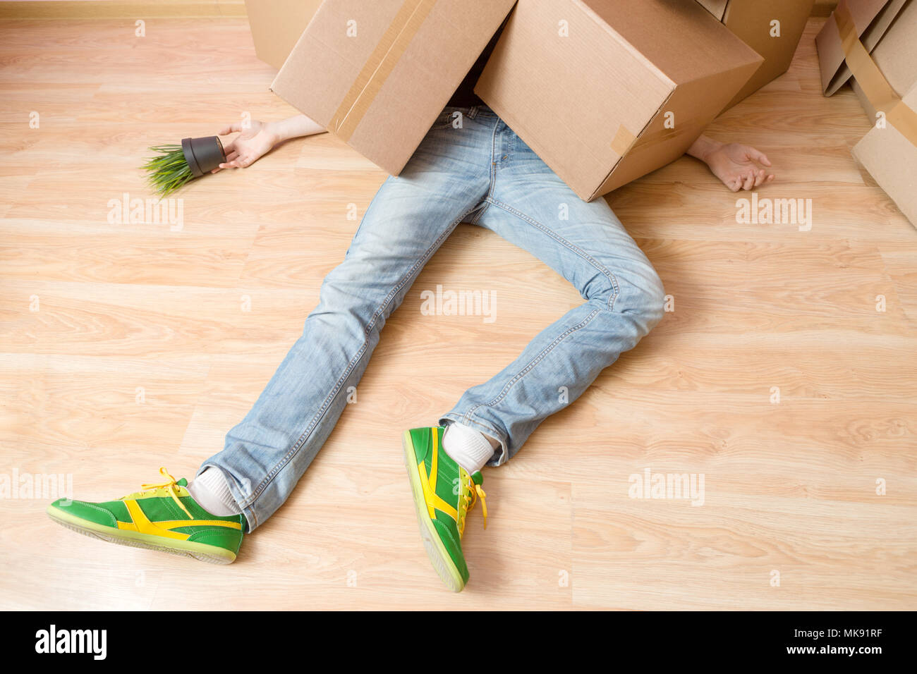 Photo of man in jeans lying under cardboard boxes Stock Photo Alamy