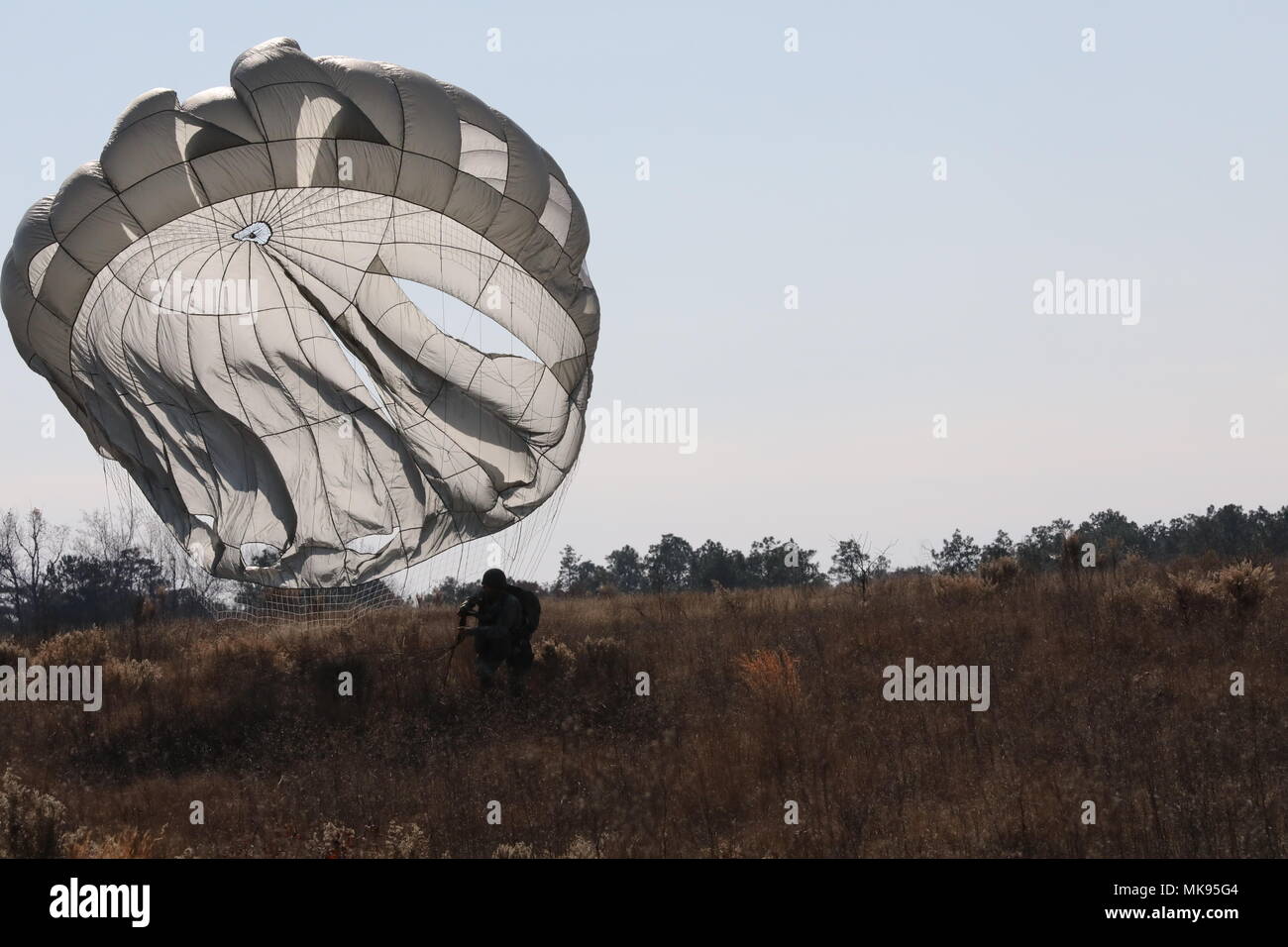 U.S. Army Jumpmaster Sgt. 1st Class Jeff Carruth assigned to the United States Army Civil Affairs and Psychological Operations Command (Airborne) prepares to land after jumping from the CASA 212 on Nov. 30, 2017 on Luzon Drop Zone, Camp MacKall, North Carolina. These jumpmasters are part of the 20th Annual Randy Oler Memorial Operation Toy Drop. This year, eight countries are participating and they include; Colombia, Canada, Latvia, the Netherlands, Sweden, Italy, Germany, and Poland. Operation Toy Drop, hosted by the U.S. Army Civil Affairs &amp; Psychological Operations Command (Airborne) an Stock Photo