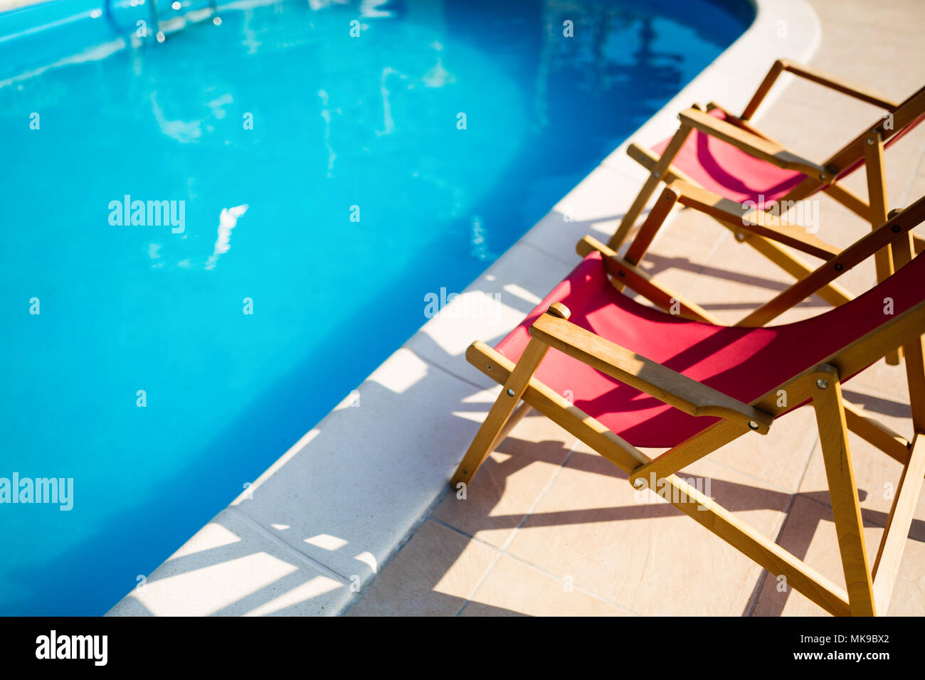Clean swimming pool with sunbathing chairs Stock Photo Alamy