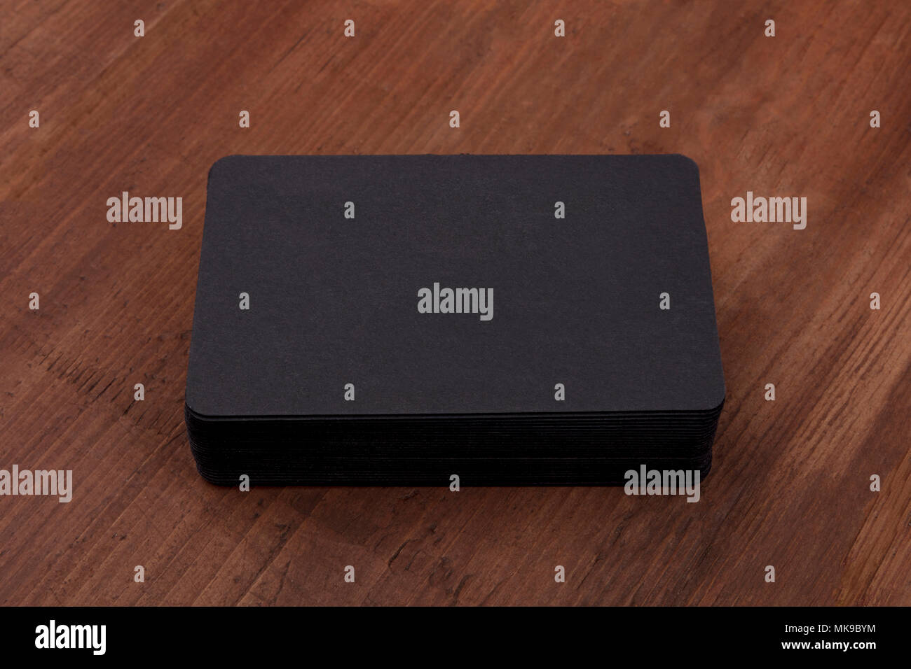 A mockup for a stack of black business cards with rounded edges on a ...