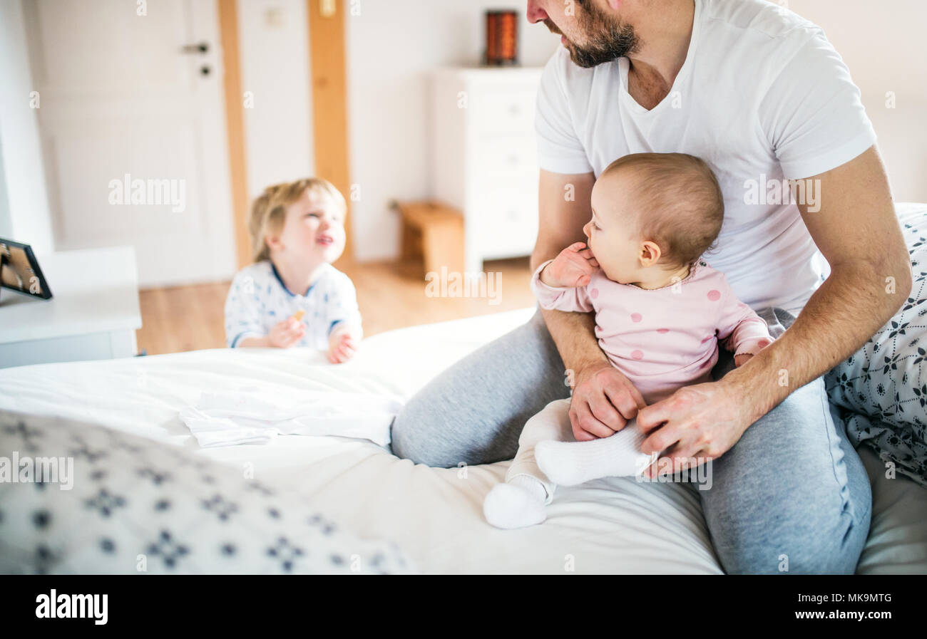 Father with toddler children in bedroom at home at bedtime. Stock Photo