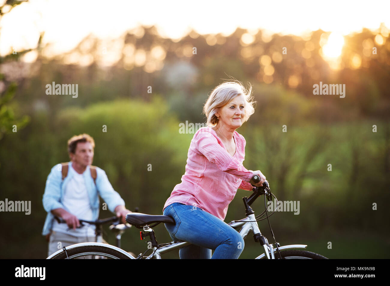 Beautiful senior couple with bicycles outside in spring nature. Stock Photo