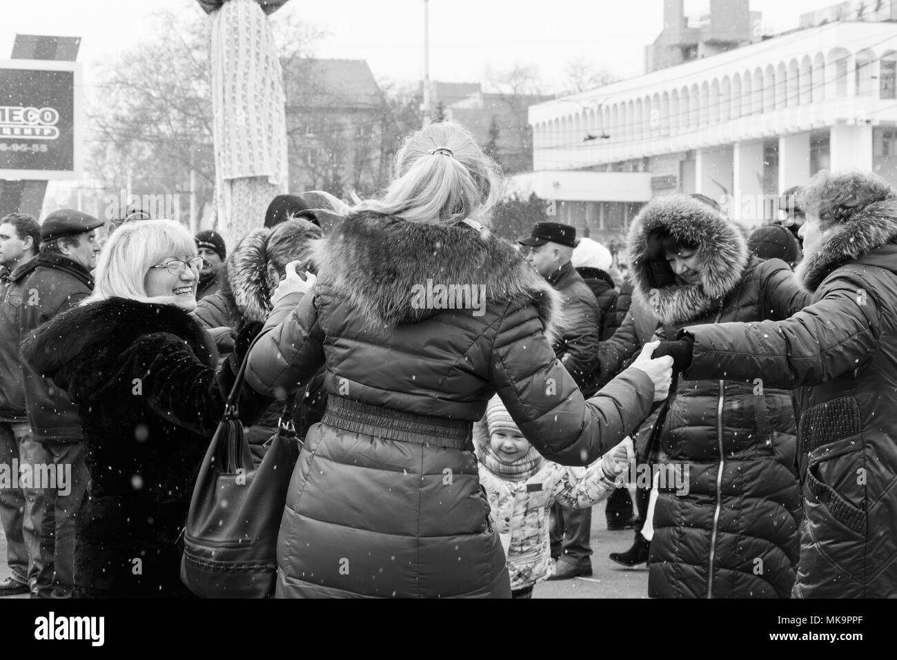 Women, men and children are dancing in the square in the center of Tiraspol, Moldova at the Shrovetide Festival. The reportage photo is black and whit Stock Photo