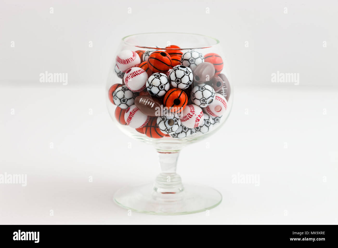 a glass of beads used to make sports related jewelry Stock Photo