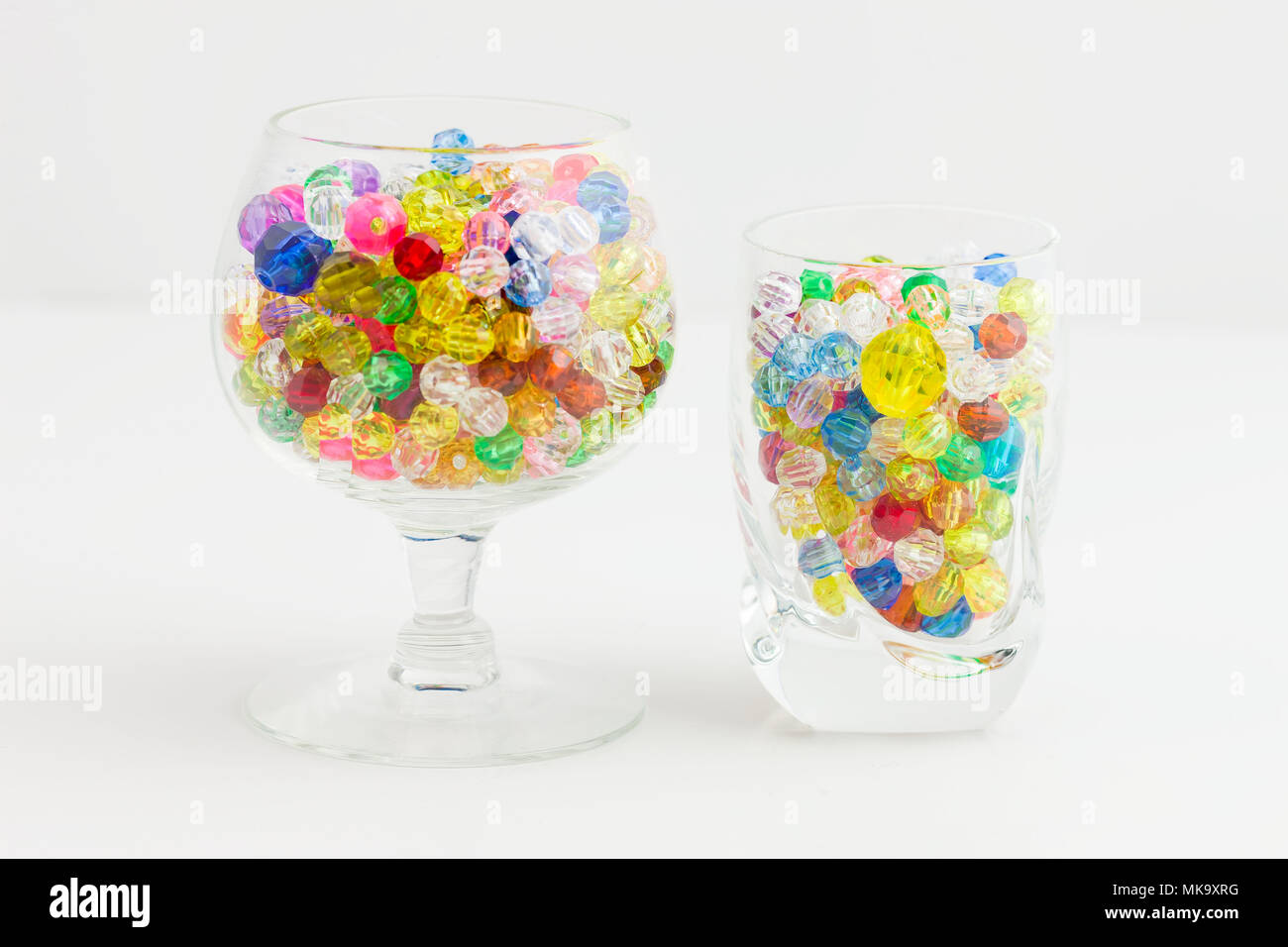 Two glasses of multi colored beads of varying sizes used to create different types of jewelry Stock Photo