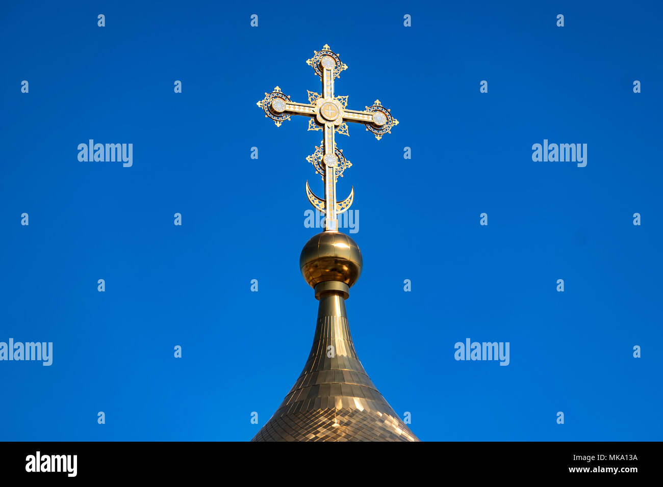 Golden Russian orthodox cross at the orthodox church roof top against blue sky Stock Photo