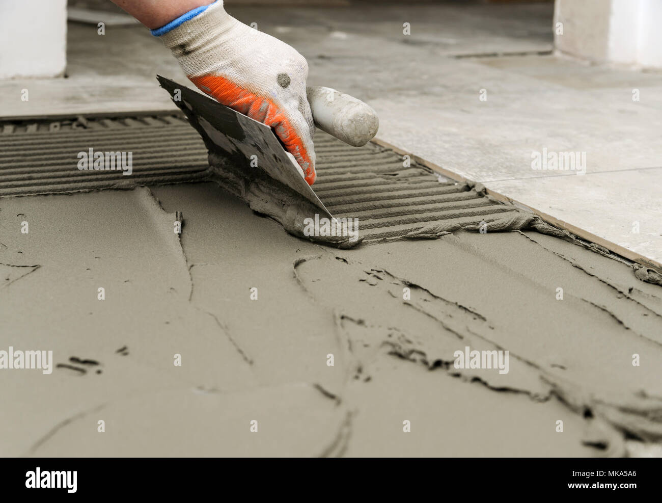 Laying Ceramic Tiles Troweling Mortar Onto A Concrete Floor In