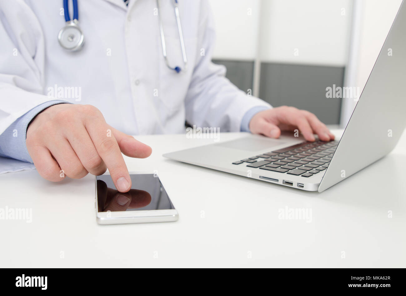 Doctor working with phone and laptop in hospital or clinic. Medical healthcare concept Stock Photo