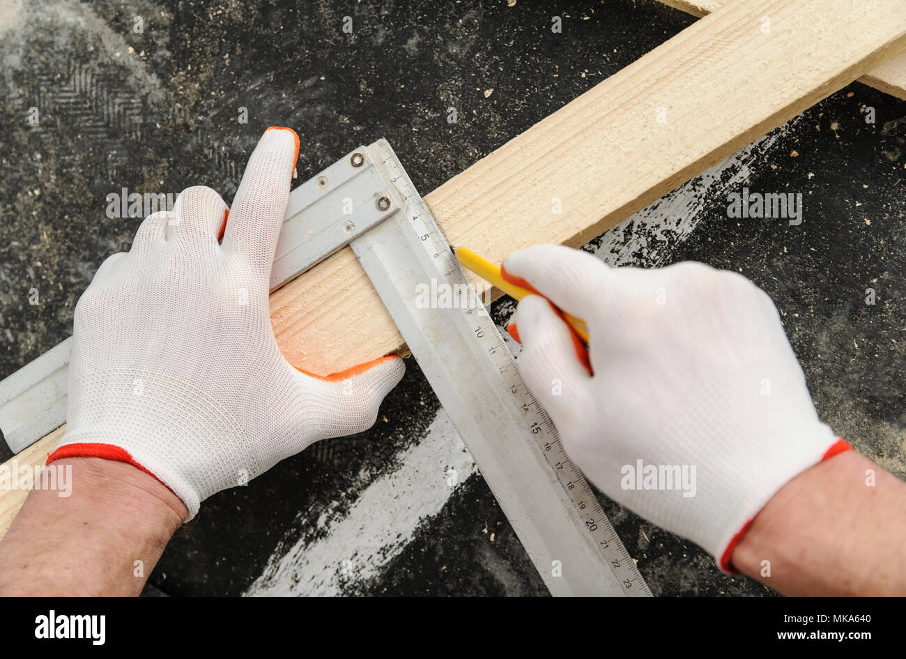 Worker measures off a wooden beam to cut it further Stock Photo - Alamy