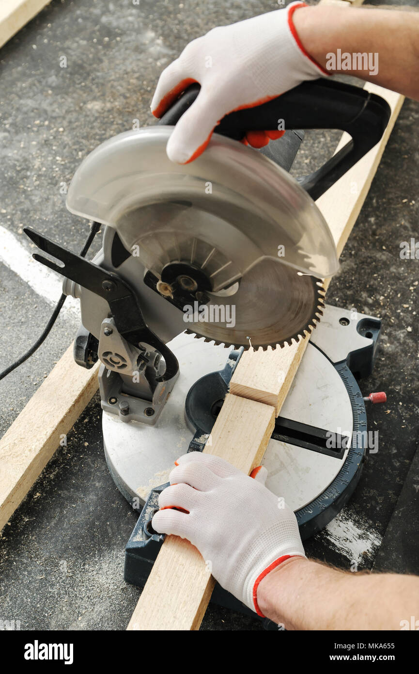 Worker cuts wood bars using a circular saw. Stock Photo