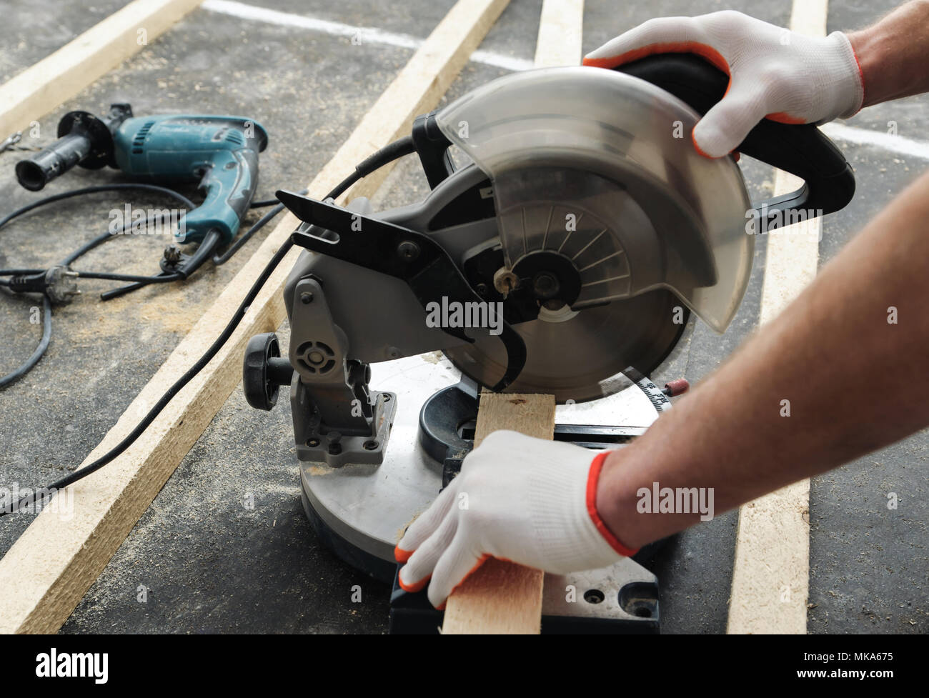 Worker cuts wood bars using a circular saw. Stock Photo