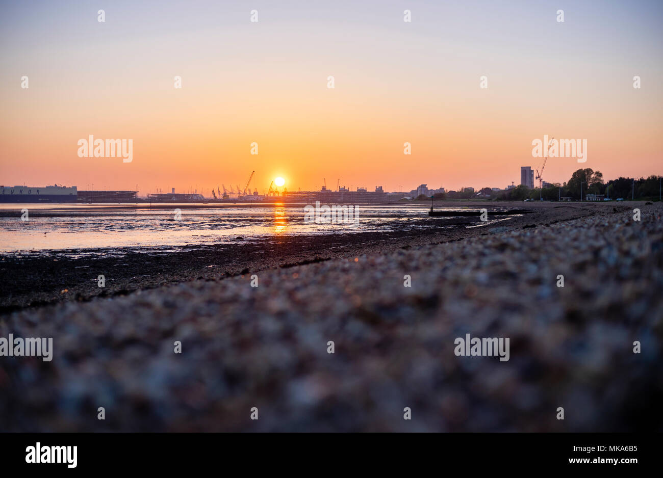 Sunset over Southampton Docks during low tide, view from Weston Shore, Hampshire, England, UK Stock Photo