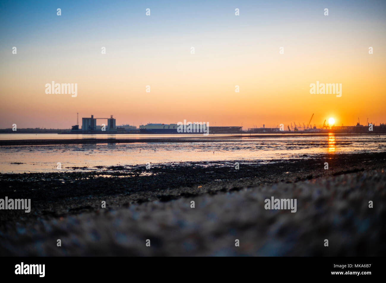 Sunset over Southampton Docks during low tide, view from Weston Shore, Hampshire, England, UK Stock Photo