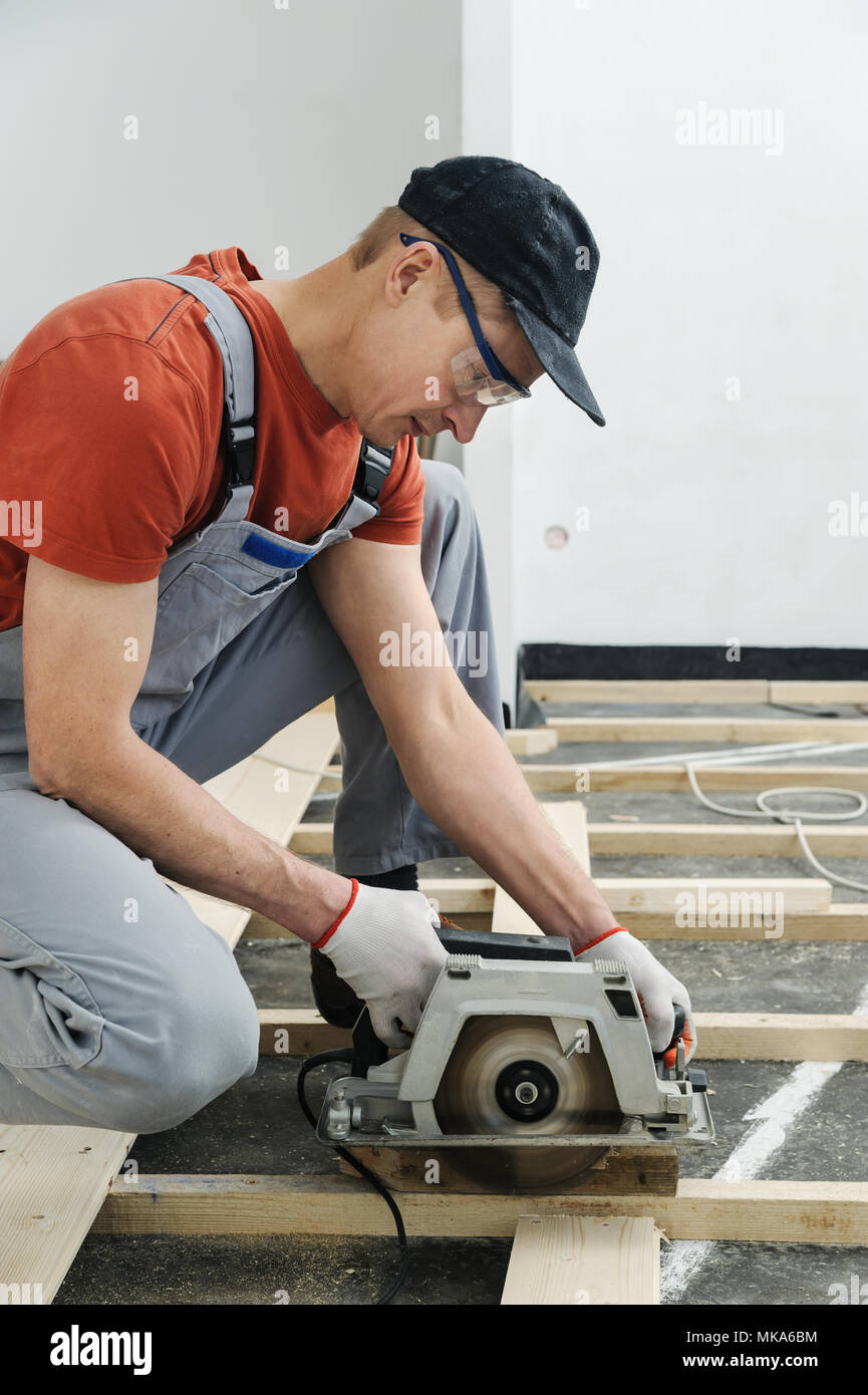 Worker cuts wooden floorboards using a circular saw Stock Photo Alamy