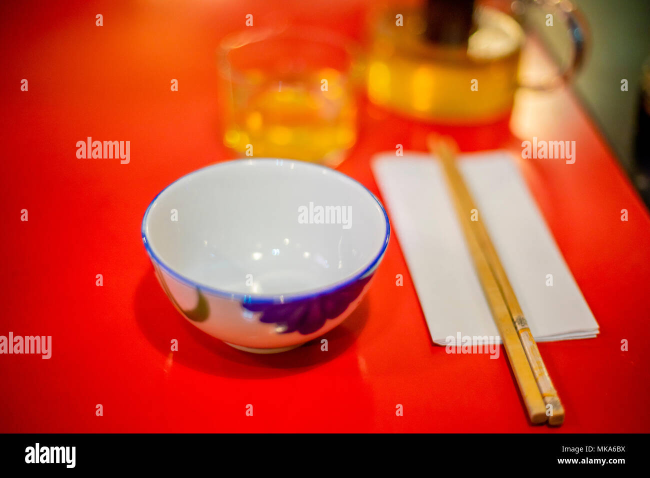 A Chinese table setting with empty rice bowl and wooden chop sticks, out of focus bokeh background Stock Photo