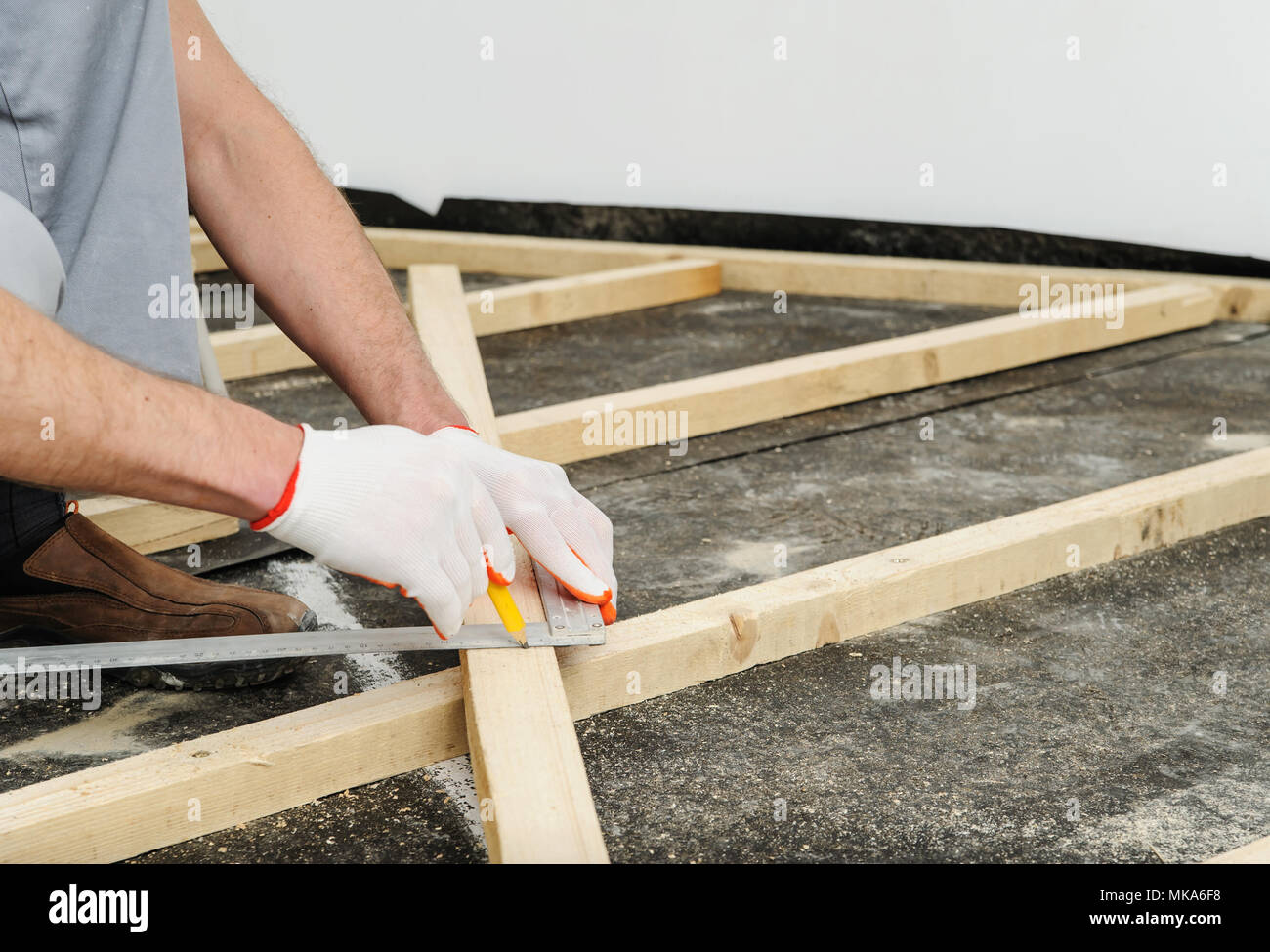 Worker measures off a wooden beam to cut it further Stock Photo - Alamy