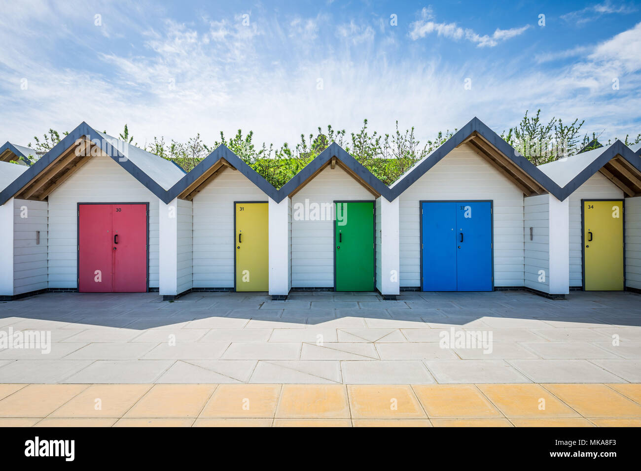 Colourful beach huts stand near the shore on a warm sunny afternoon in the coastal town of Swanage, Dorset, UK. Stock Photo