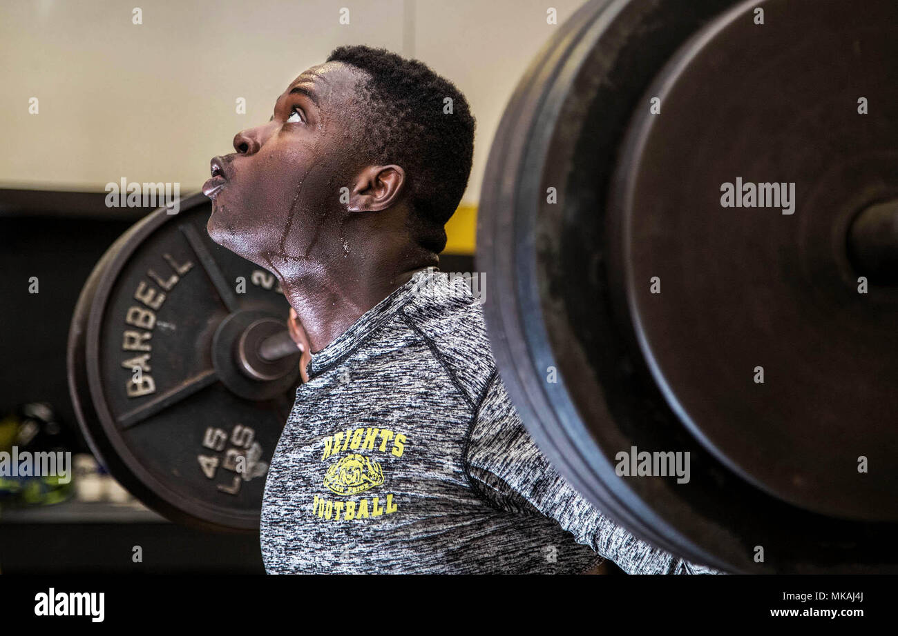 Boca Raton, Florida, USA. 7th May, 2018. Sebastian Bruno works out in the weight room at Olympic Heights Community High School in Boca Raton, Florida on May 7, 2018. When Sebastian Bruno's mom put him and his younger brother on a military plane out of Port Au Prince, Haiti in the weeks after the earthquake, she was certain he was going to be the better for it. But the 9-year-old wasn't so sure - staying with an uncle he knew only from a couple of visits, in a land that looked nothing like home and where he didn't speak the language. But now he's looking forward too - he discovered a knack for Stock Photo