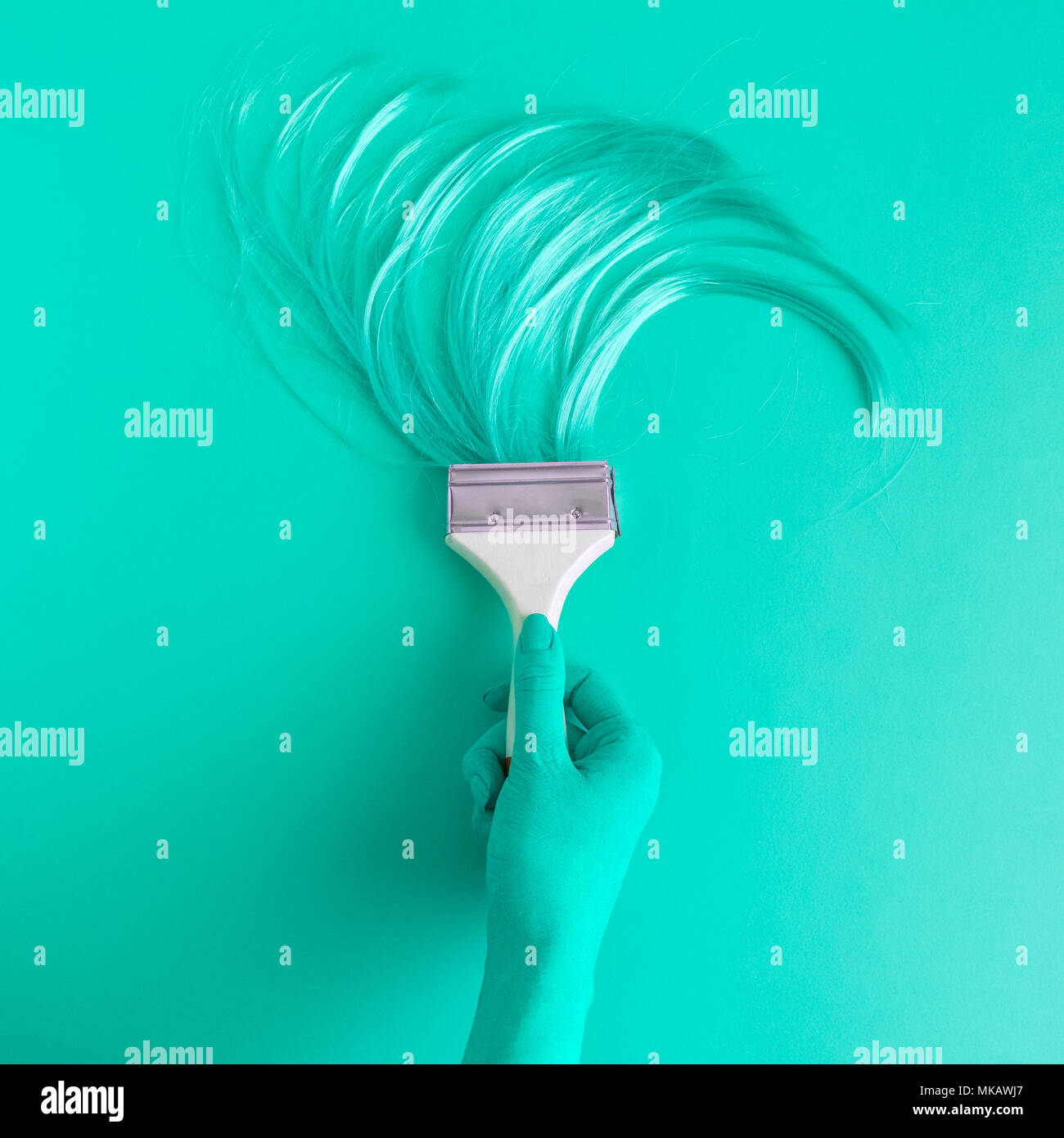 Hand holding paintbrush with long hair minimal abstract turquoise creative concept. Stock Photo