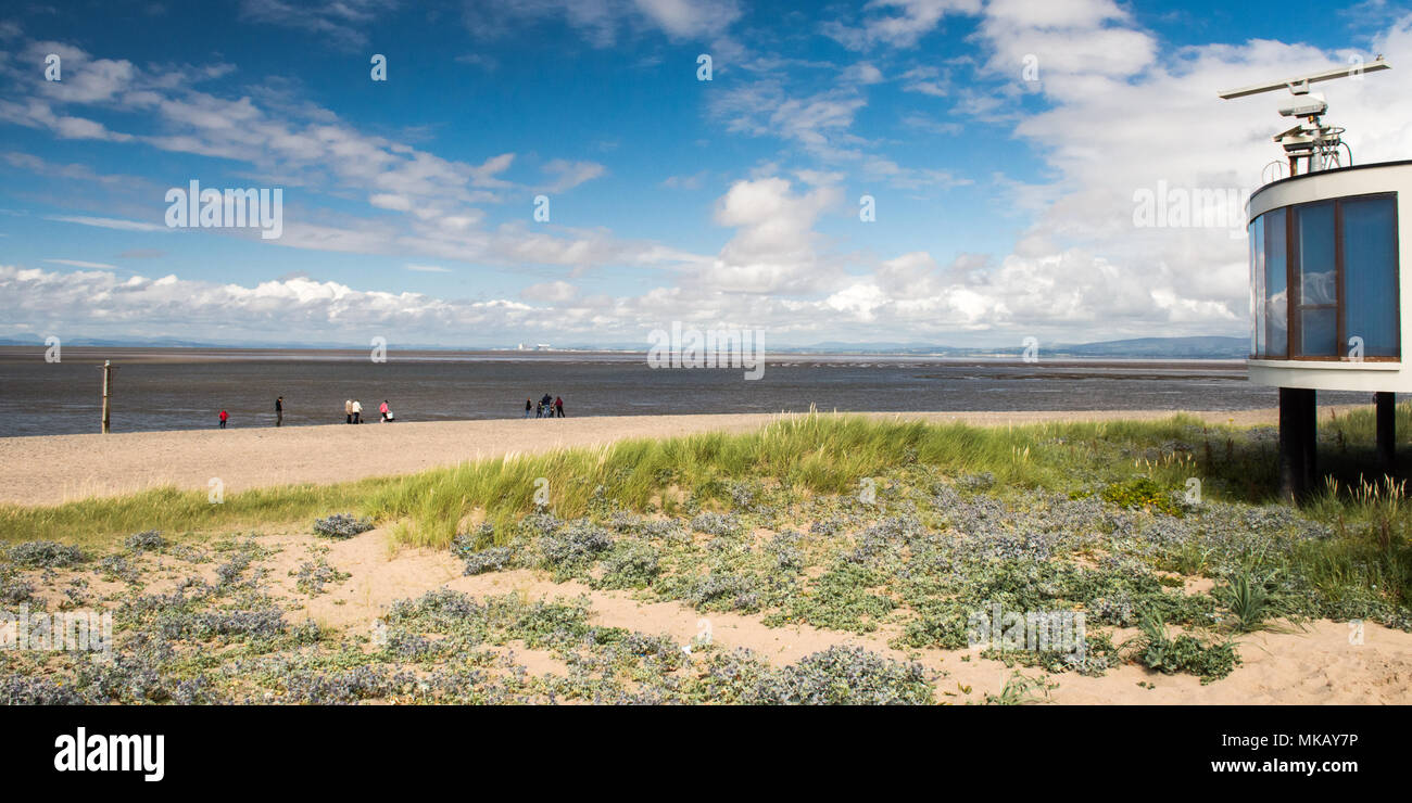 People walk along the sands of Fleetwood Beach near Blackpool in Lancashire, with the mountains of the Lake District and Bowland in the distance acros Stock Photo