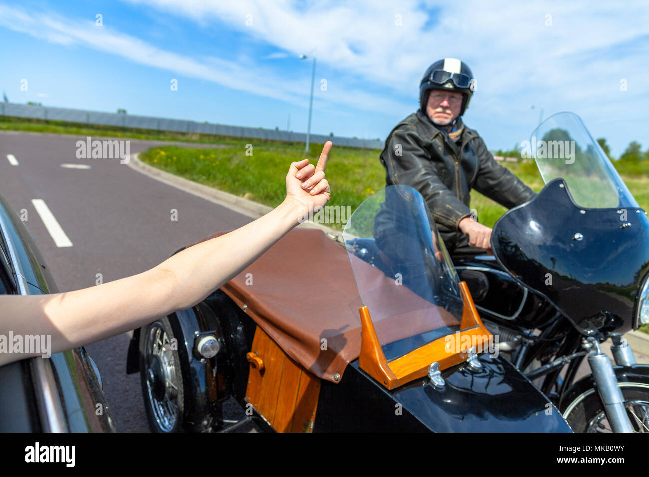 a car driver shows his middle finger to a  biker Stock Photo