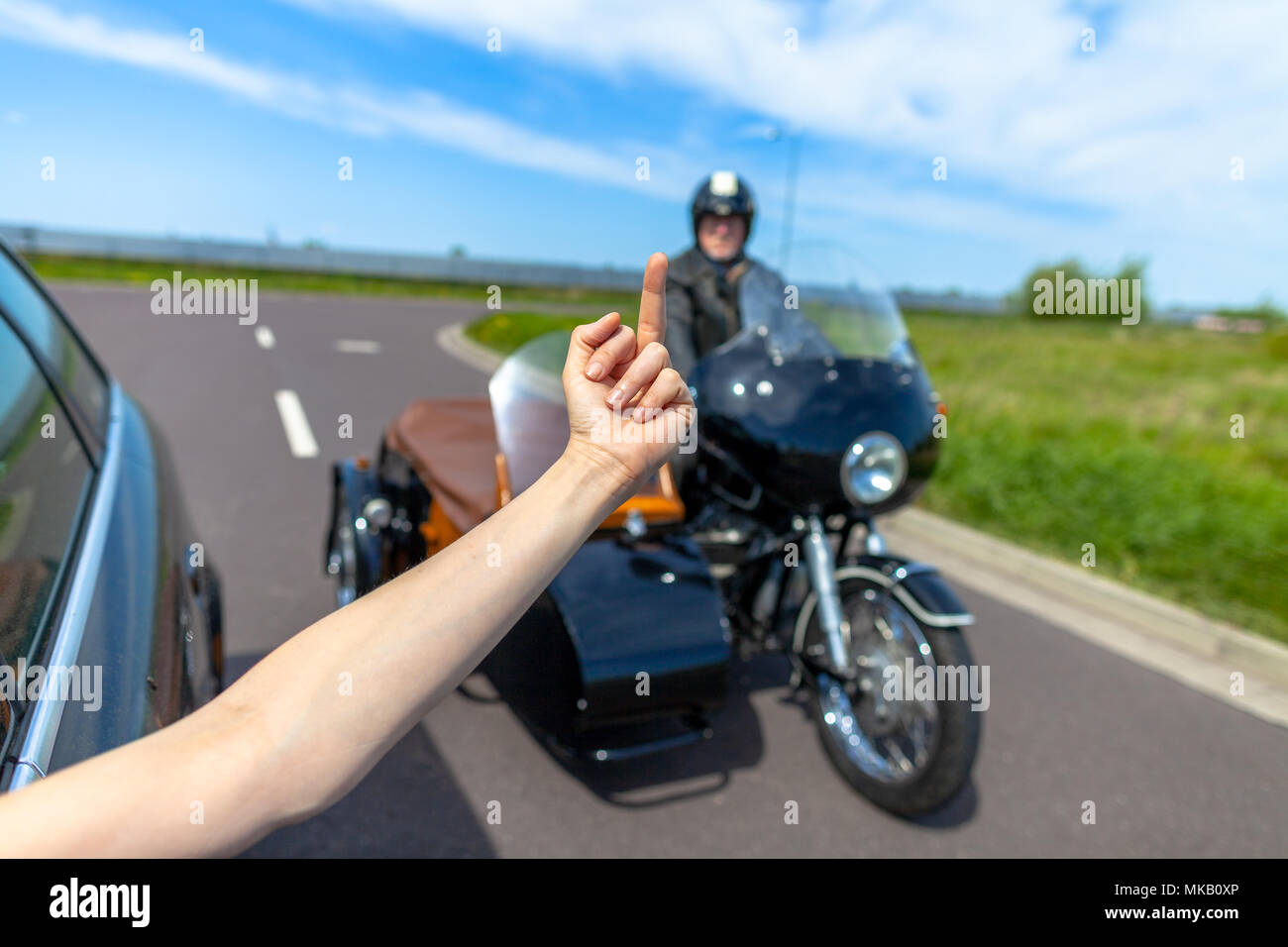 a car driver shows his middle finger to a  biker Stock Photo