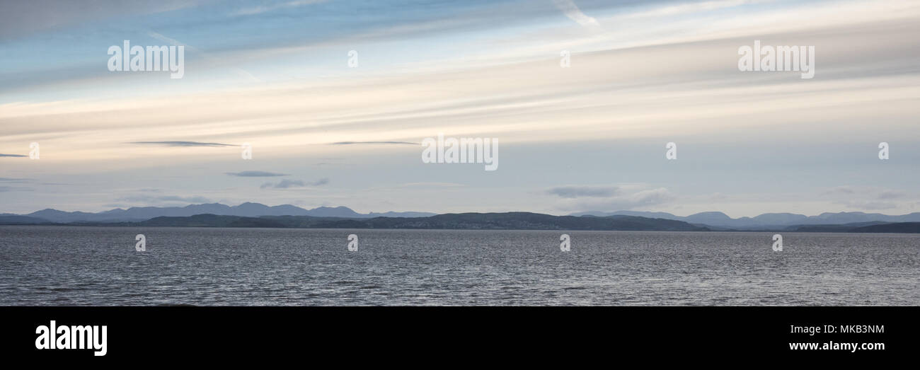 The mountains of Cumbria's Lake District rise behind the waters of Morecambe Bay in the Irish Sea, viewed from Morecambe in Lancashire. Stock Photo