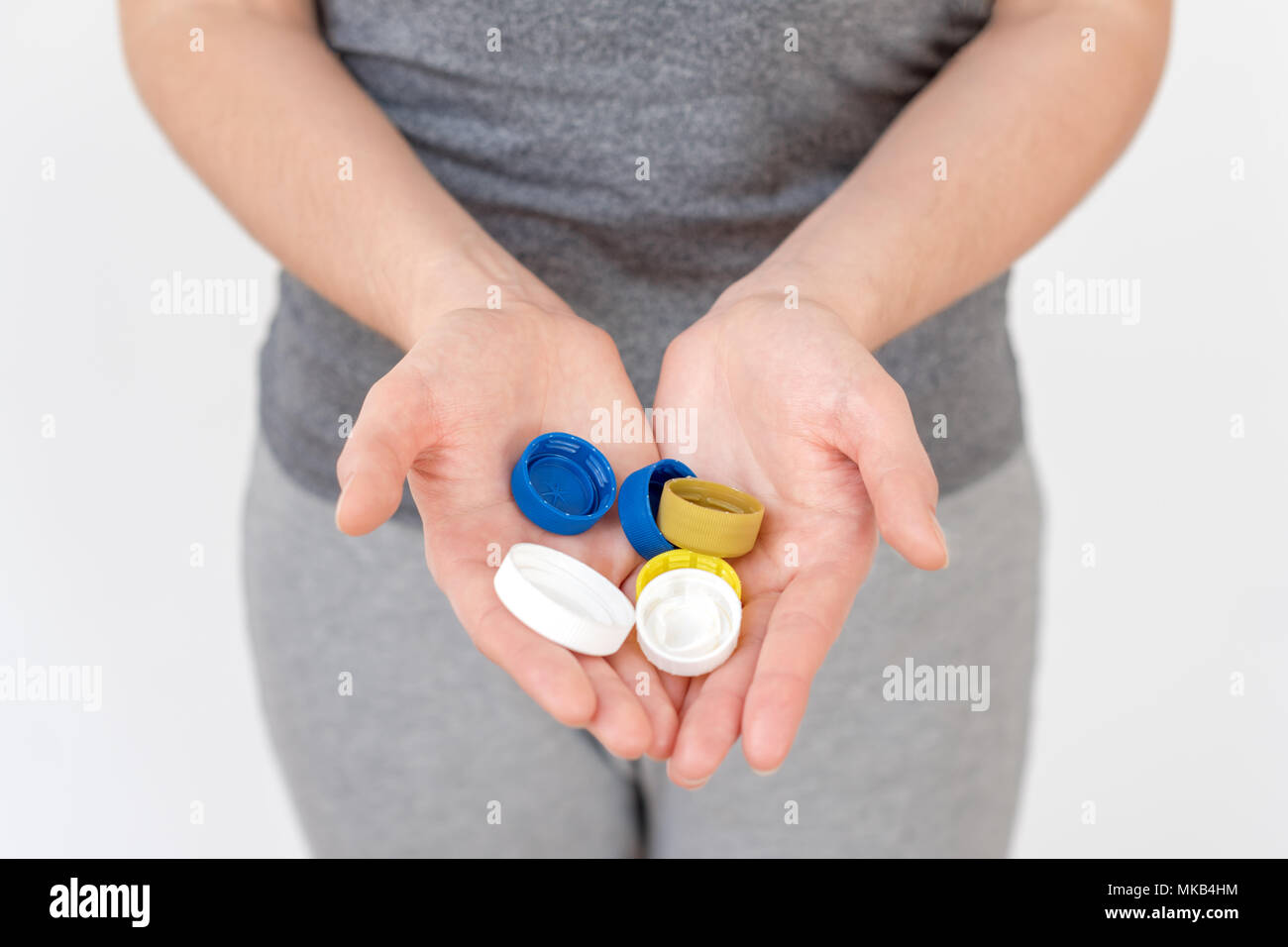 Female hand holding plastic bottle caps. Two hands with plastic lids