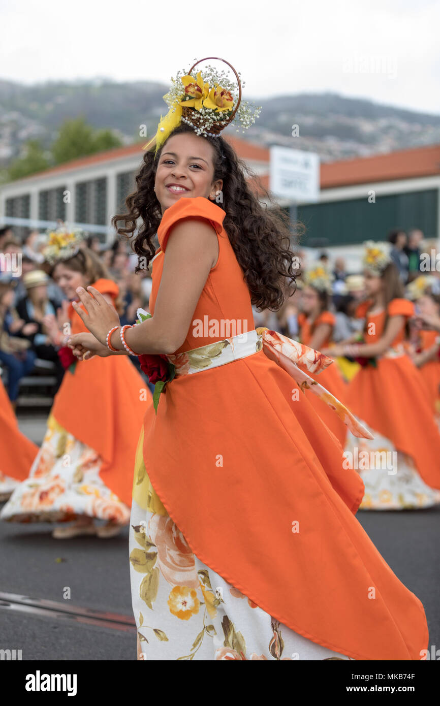 Funchal; Madeira; Portugal - April 22; 2018: A group of girls in orange costumes are dancing at Madeira Flower Festival Parade in Funchal on the Islan Stock Photo