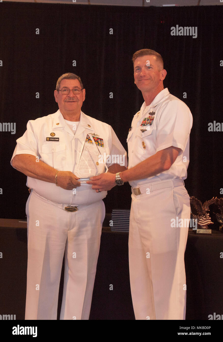 Alan Starr, Third Vice President of the Fort Lauderdale Navy League (left), presents an award to Master Chief Petty Officer (MCPO) Jason Knupp, MCPO of Expeditionary Strike Group Two (right), during the Enlisted Person of the Year Event in Fort Lauderdale, May 3, 2018. The Enlisted Person of the Year Event highlights Marines and Sailors that have gone above and beyond in their performances amongst their peers. (U.S. Marine Corps photo by Staff Sgt. Leon M. Branchaud) Stock Photo