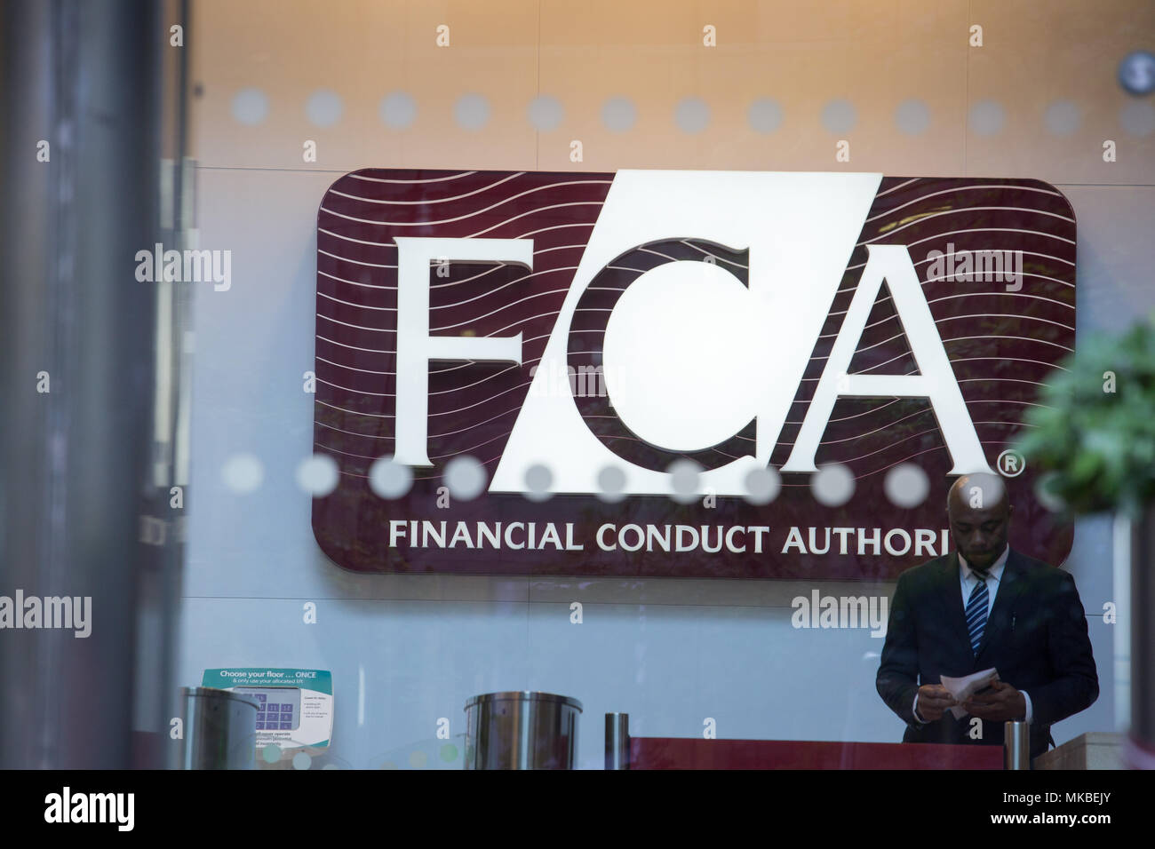 Financial Conduct Authority (FCA) offices, North Colonnade, Docklands, London. Reception with security guard standing next to visitor gate Stock Photo