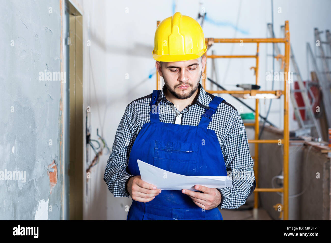 Diligent  builder is looking on the project of work for the object. Stock Photo