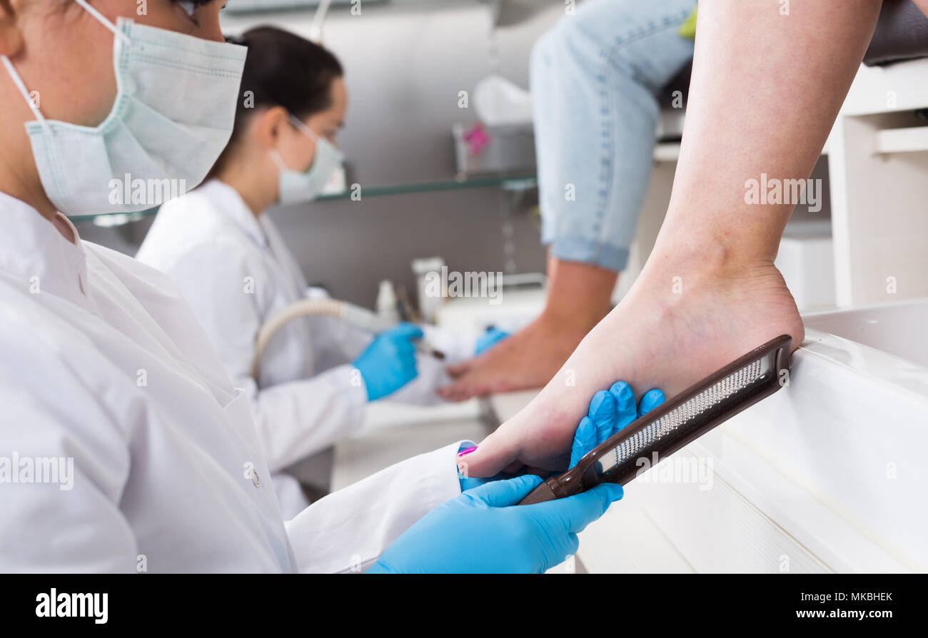 Nail master performing pedicure and foot reflexology in beauty salon