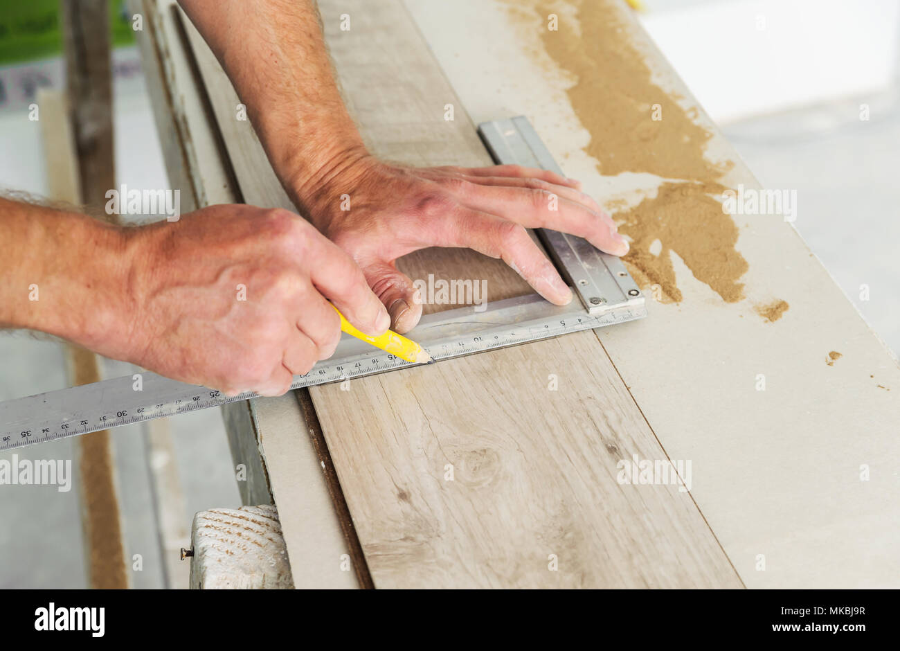 Installing Laminate Flooring Worker Measures Off A Piece Of Board