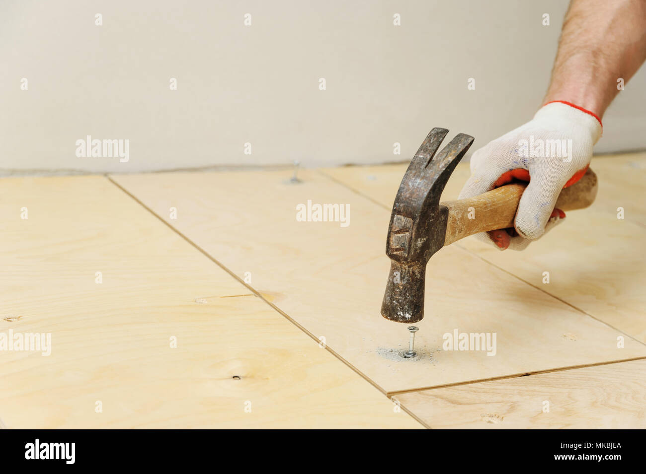 Laying plywood on the floor. Worker inserts the dowel to fix a plywood